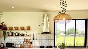 A modern kitchen with a large island, wooden stools, and a view of greenery outside. - Chacha Tyme Pool Villa Khaoyai (Pak Chong)