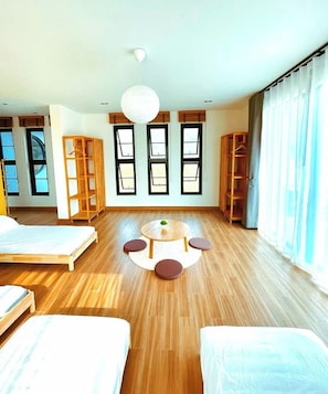 A spacious room with wooden flooring, a round table with chairs, and built-in shelving units.