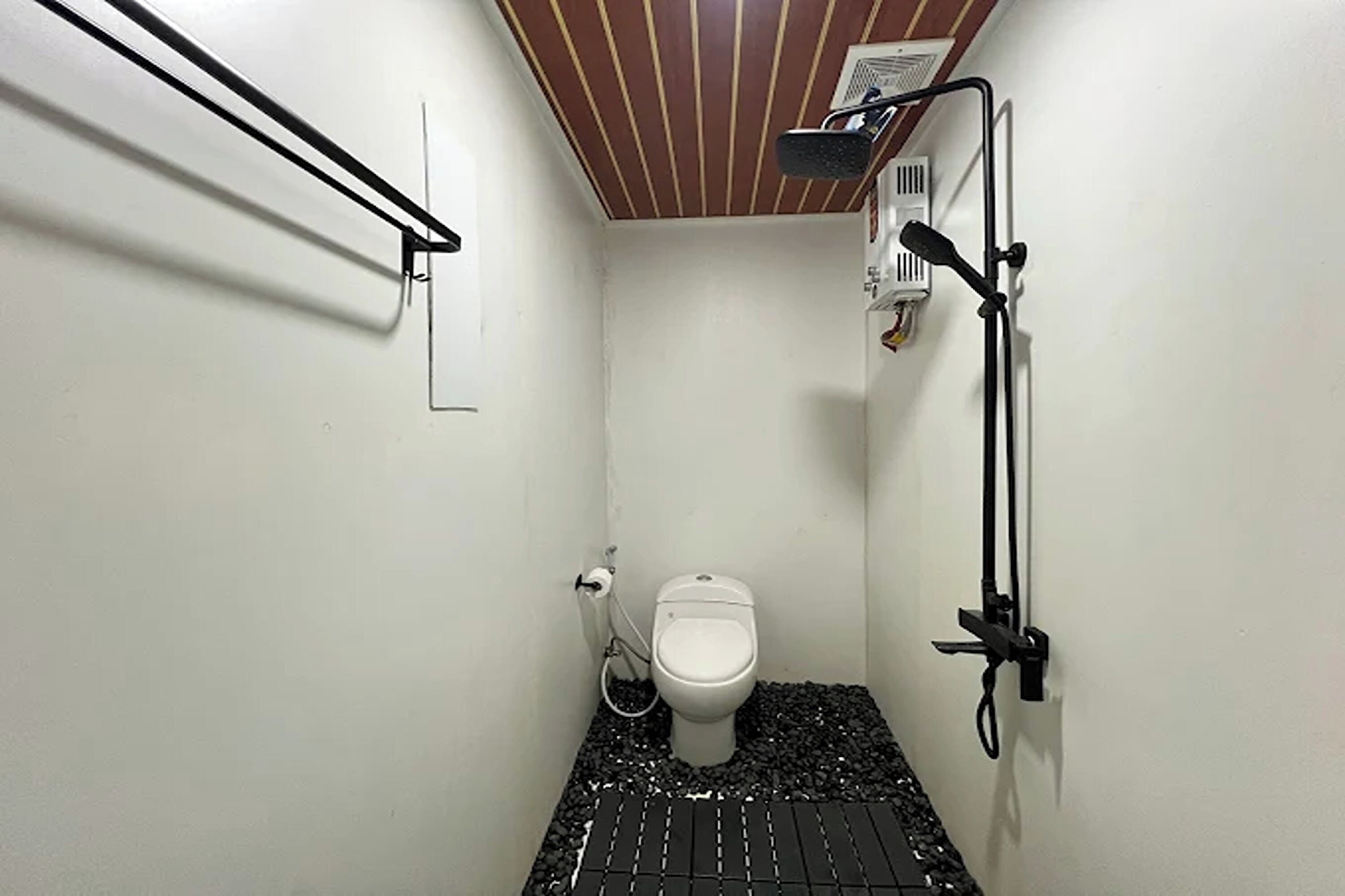 Un baño pequeño y funcional con inodoro, ducha y barra para toallas.