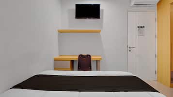 A bedroom with a bed, a desk, a chair, a TV, and a wardrobe.