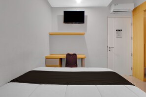 A bedroom with a bed, a desk, a chair, a TV, and a wardrobe. - Hotel O near Taman Sriwedari formerly In (Surakarta)