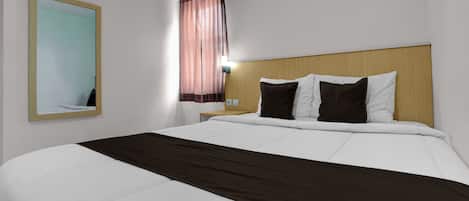 A hotel room with a bed, a nightstand, a mirror, and a window with curtains.