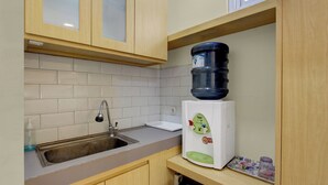 A kitchen with a sink, faucet, countertop, and a water dispenser. - Hotel O near Taman Sriwedari formerly In (Surakarta)