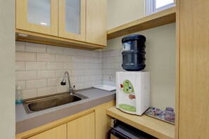 A kitchen with a sink, faucet, countertop, and a water dispenser. - Hotel O near Taman Sriwedari formerly In (Surakarta)