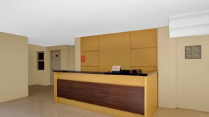 A reception desk with a wooden panel design, a door to the left, and a small window on the right wall. - Hotel O near Taman Sriwedari formerly In (Surakarta)