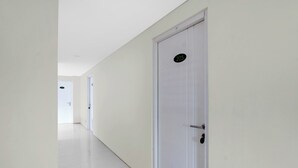 A hallway with white walls and doors, one marked with the number 205. - Hotel O near Taman Sriwedari formerly In (Surakarta)