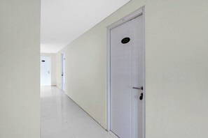 A hallway with white walls and doors, one marked with the number 205. - Hotel O near Taman Sriwedari formerly In (Surakarta)