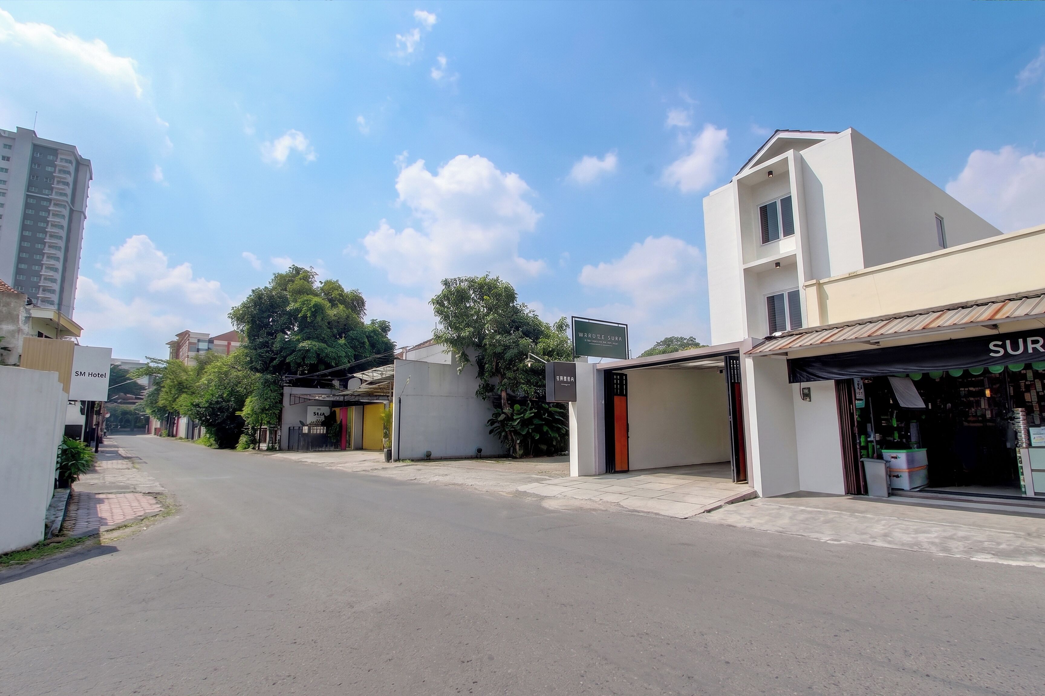 Vista de una calle con edificios, un letrero que dice 'SM Hotel' y un escaparate con un letrero que indica 'SUR'.