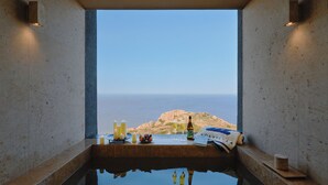 A spa area with a view of the sea, a towel, a bottle, and candles.
