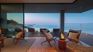 A balcony with wicker furniture, a table with candles, and a view of the sea.