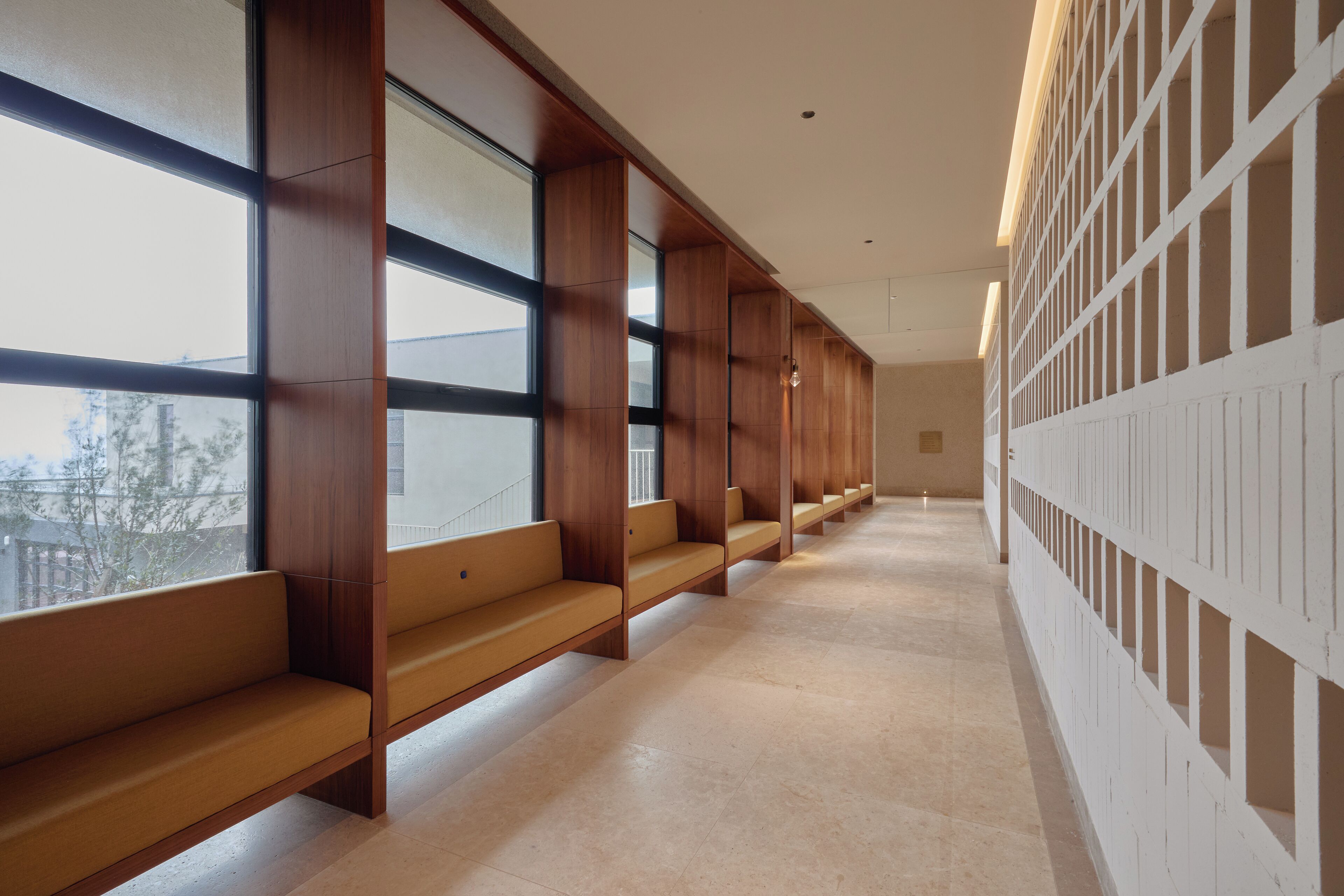 A corridor with wooden benches and large windows.