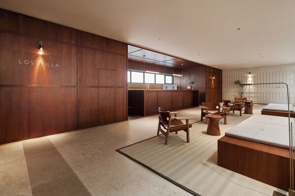 Un moderno vestíbulo de hotel con paneles de madera, una recepción, zona de estar y un amplio ventanal.