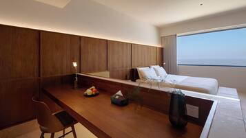 Habitació d'hotel moderna amb escriptori de fusta, un llit i una finestra gran.