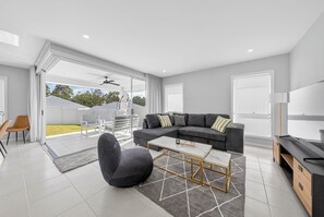 A modern living room with a sectional sofa, a coffee table, and a TV. - Huntlee Hideaway | 5BR Stay at Hunter Region (North Rothbury)