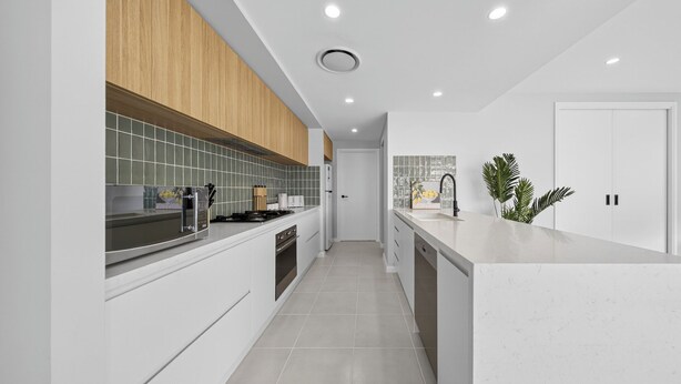 Una cocina moderna con armarios blancos, una sección superior de madera y salpicadero de azulejos.