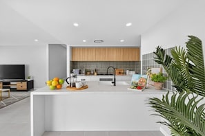 A modern kitchen with a central island, a built-in oven, and a large window above the sink. - Huntlee Hideaway | 5BR Stay at Hunter Region (North Rothbury)