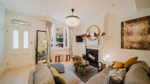 A living room with a fireplace, a chandelier, and a large abstract painting.