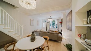 A modern living room with a round dining table, a sofa, and a chandelier.