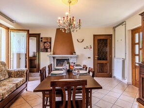 A dining area with a table set for four, a chandelier, and a fireplace. - Cascina Rossa by Interhome (Osteno)