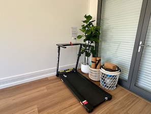 A room with a treadmill, a potted plant, and a basket with items. - Designer 4-Bed Coastal Home Walk To Beach & Shops (Maroubra)