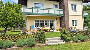 A two-story building with a balcony, a dining area with outdoor seating, and a garden. - Haus Kühnsdorf by Interhome (Klopeiner See)