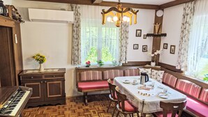 A cozy dining area with a wooden table, chairs, a bench, and a piano. - Haus Kühnsdorf by Interhome (Klopeiner See)
