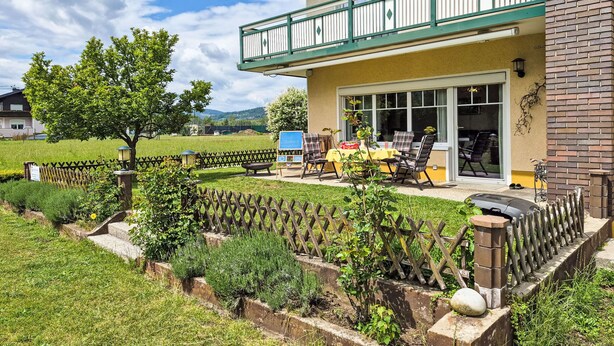 A two-story building with a balcony, a patio with outdoor furniture, and a fenced garden area. - Haus Kühnsdorf by Interhome (Klopeiner See)