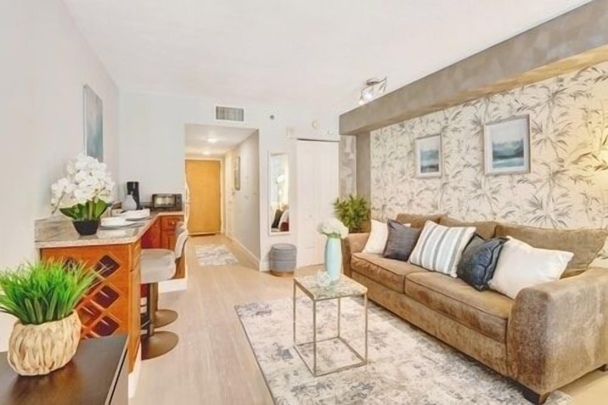 A modern living room with a sofa, coffee table, and a kitchen area in the background.
