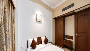 A hotel room with a bed, a bedside table, a wardrobe, and a mirror. - Hotel Royal Plazha (Chennai)