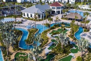 A resort with multiple swimming pools, palm trees, and a building with a red roof. - Themed Disney Villa 6BD Resort WaterSlide Pool Spa (Kissimmee)