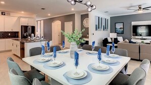 A modern dining area with a white table set for six, surrounded by grey chairs.