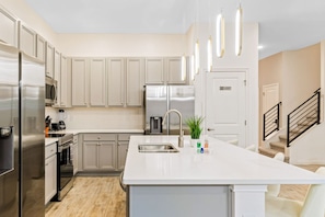 A modern kitchen with stainless steel appliances, a central island, and pendant lighting. - Sleep 25 Seaworld Disney 10BD Lakeview Pool Resort (Orlando)