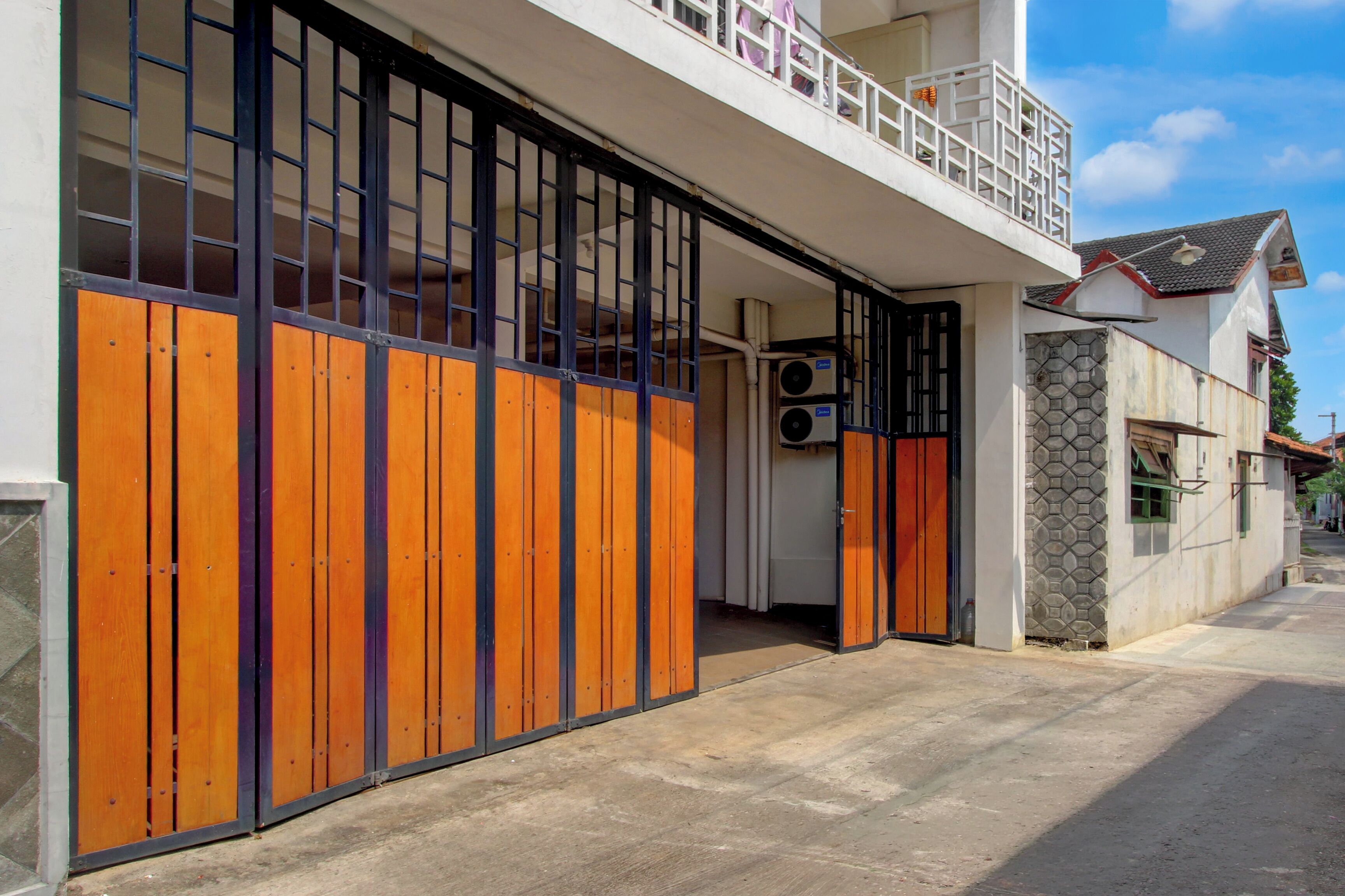 A building with a large wooden gate, a balcony, and an air conditioning unit.