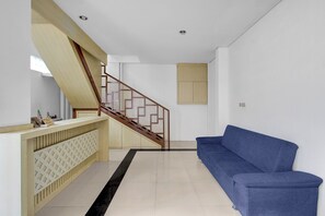 A modern interior with a staircase, a blue sofa, and a wooden reception desk.