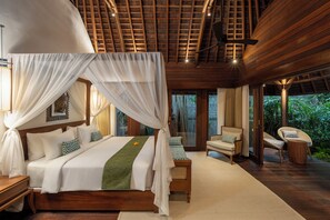 A bedroom with a canopy bed, wooden furniture, and a view of greenery outside. - The Suaka Bali Aga (Seminyak)