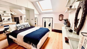 A bedroom with a large bed, skylight, built-in wardrobe, and a mirror.