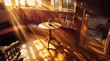A room with a wooden floor, a round table with a lantern, and a bench.