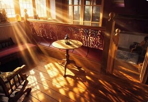 Una habitación con suelo de madera, una mesa redonda con un farol y un banco.