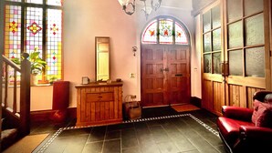 A room with a wooden door, a mirror, a bench, and a potted plant.