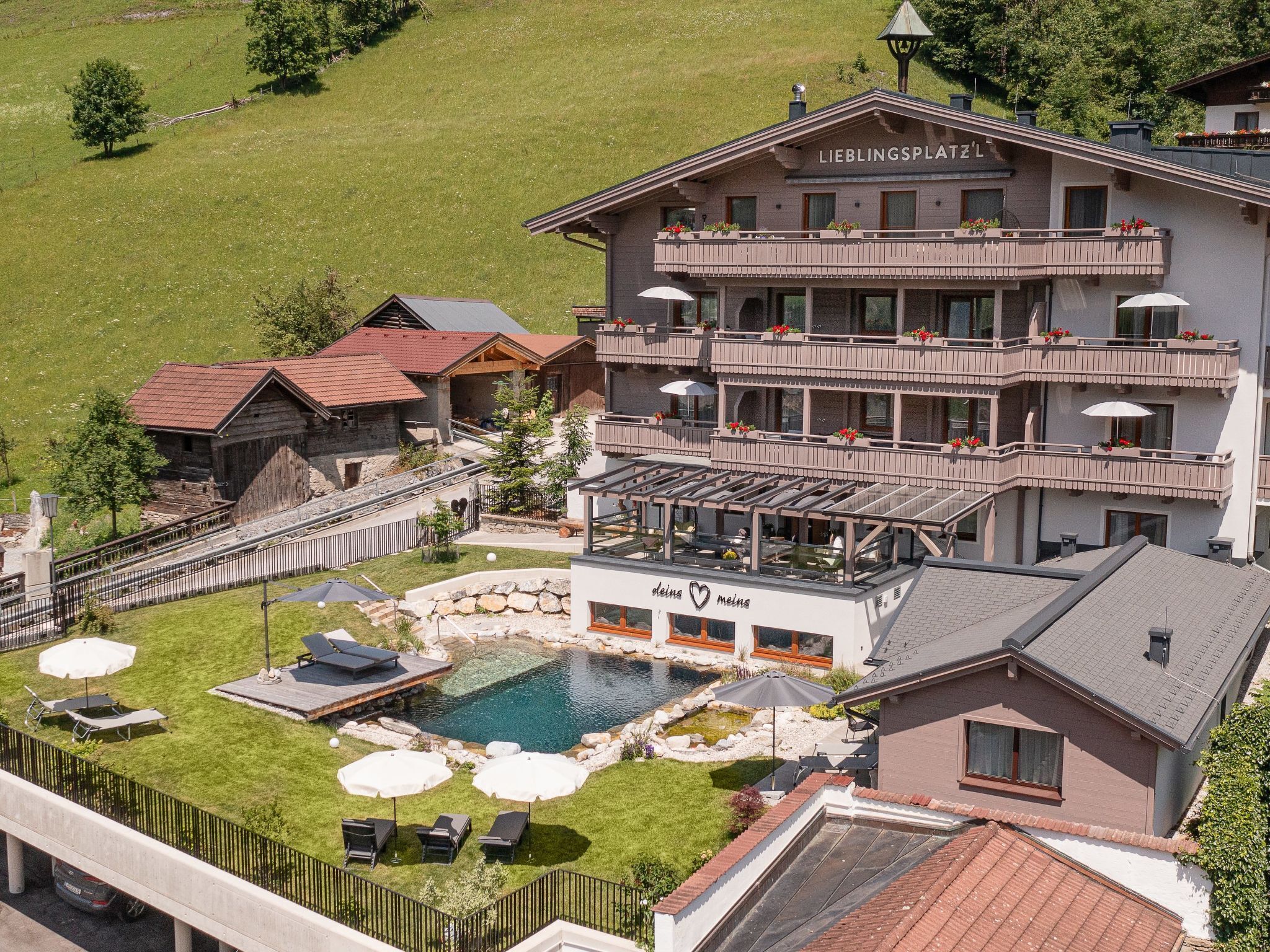 A hotel with a pool, outdoor seating, and a sign reading 'LIEBLINGSPLATZ'.