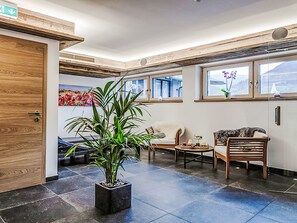Eine Lobby mit einer Rezeption, einem Blumentopf, einer Sitzecke und großen Fenstern.