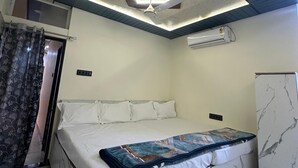 Un dormitorio con cama, ventilador de techo, unidad de aire acondicionado y un mueble con diseño de mármol.
