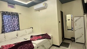 Una habitación moderna con un sofá blanco, un lámpara en el techo, un equipo de aire acondicionado y un refrigerador con diseño de mármol.