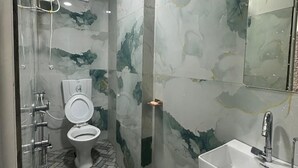 Un baño con inodoro, lavamanos, ducha y suelo de baldosas.