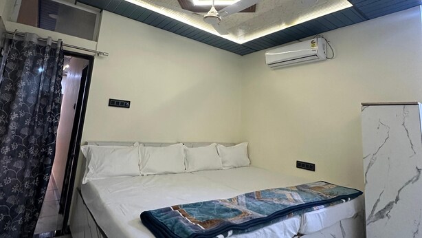 Un dormitorio con cama, ventilador de techo, unidad de aire acondicionado y un mueble con diseño de mármol.