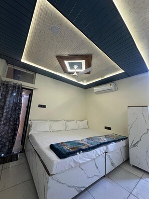 Un dormitorio con cama, ventilador de techo, unidad de aire acondicionado y un mueble con diseño de mármol.