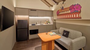 A compact living space with a kitchenette, a sofa, a small table, and a flat-screen TV. - lyf Chinatown Singapore (Singapore)