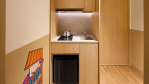 A compact kitchen with wooden cabinets, a stainless steel sink, and a black dishwasher. - lyf Chinatown Singapore (Singapore)