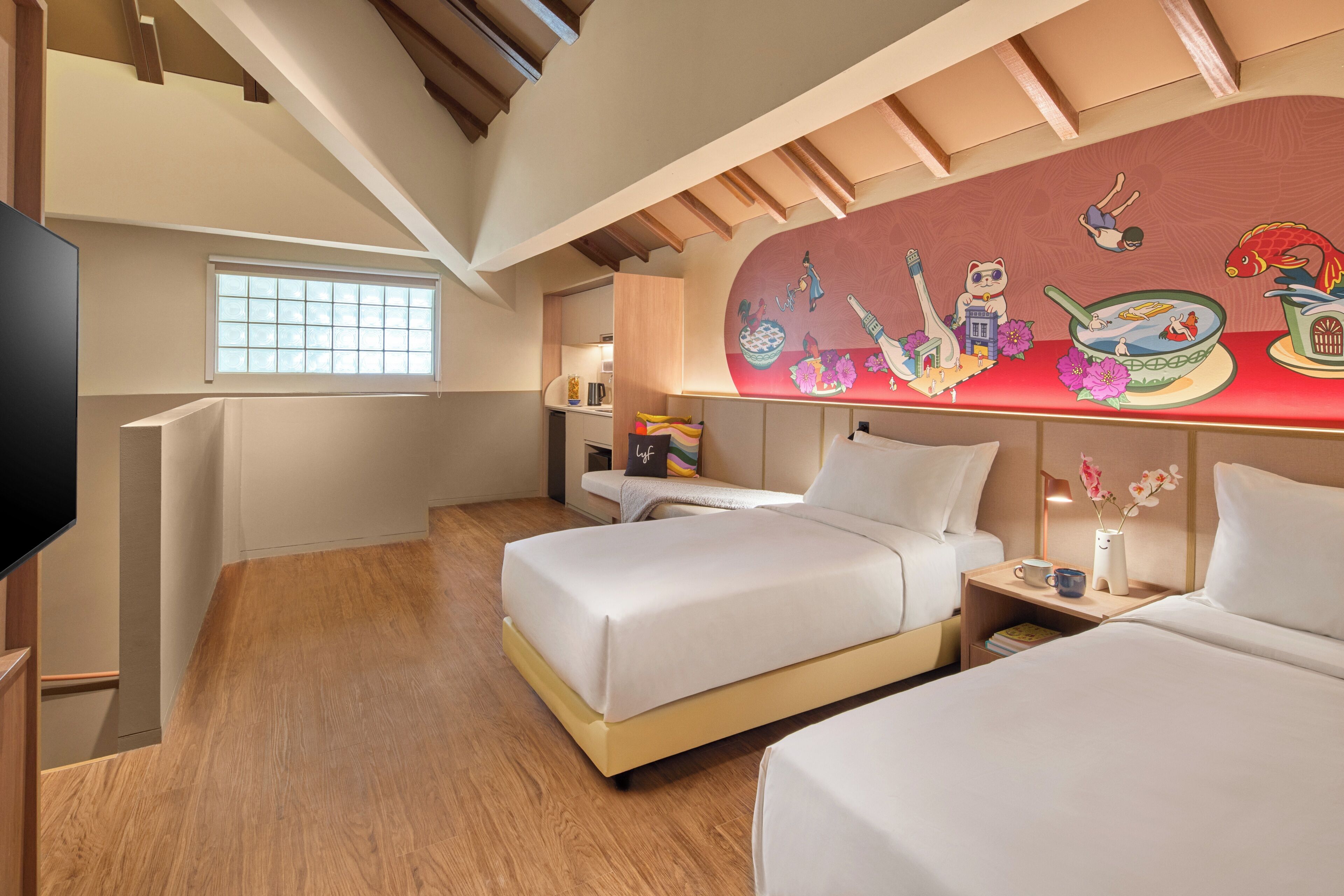A hotel room with two beds, a TV, a window, and a mural on the wall.