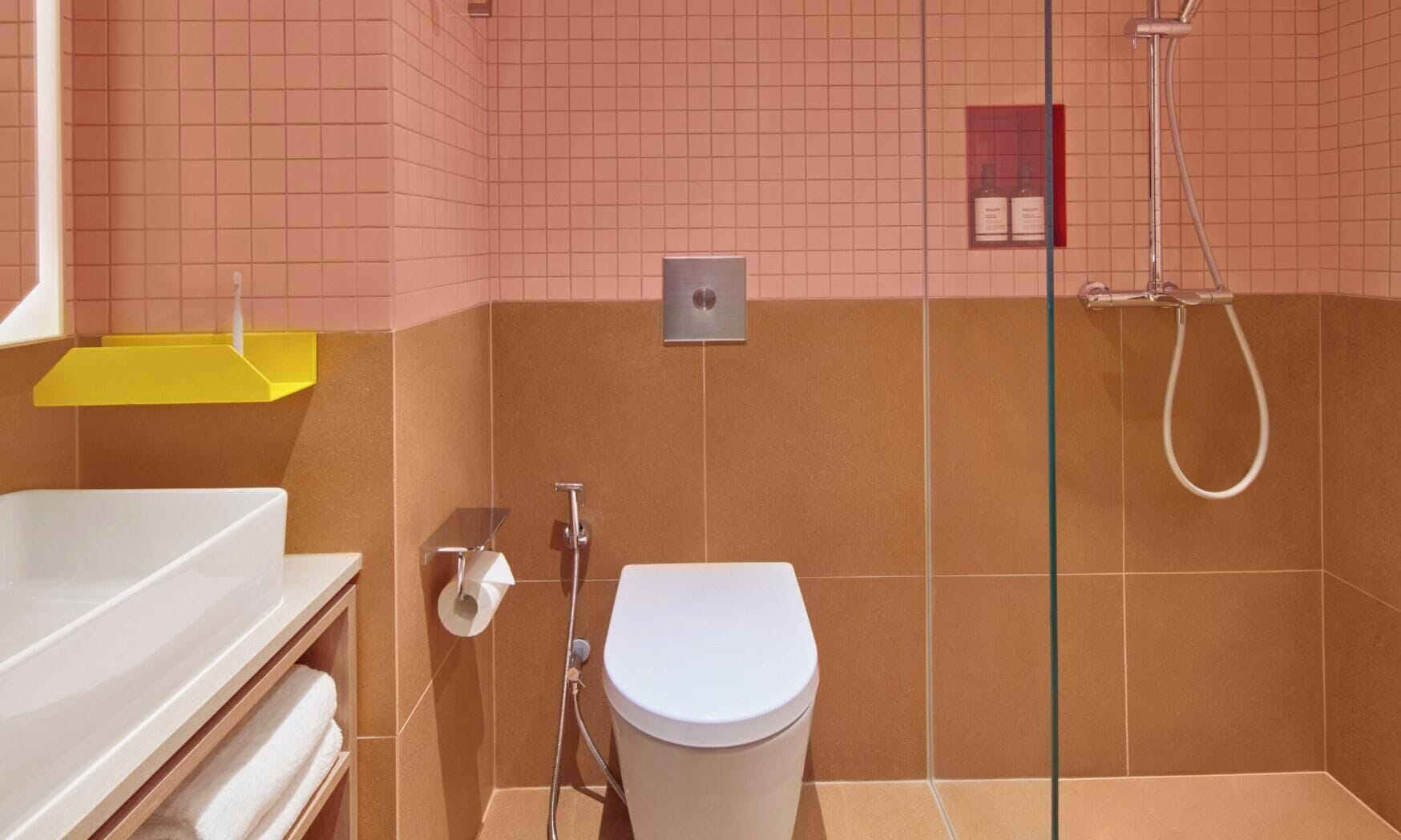 A bathroom with a white toilet, a shower, and a yellow shelf.
